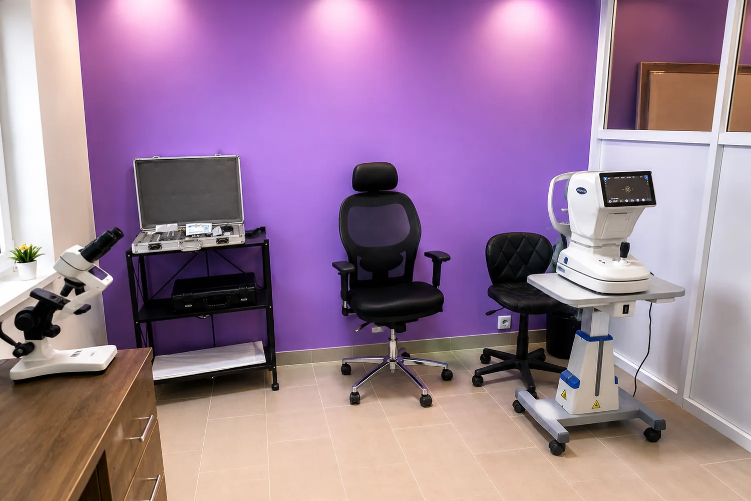 Modern eye examination room at Elite Eyes and Opticals in Lekki, Lagos, featuring diagnostic eye care equipment, an examination chair and a purple accent wall.